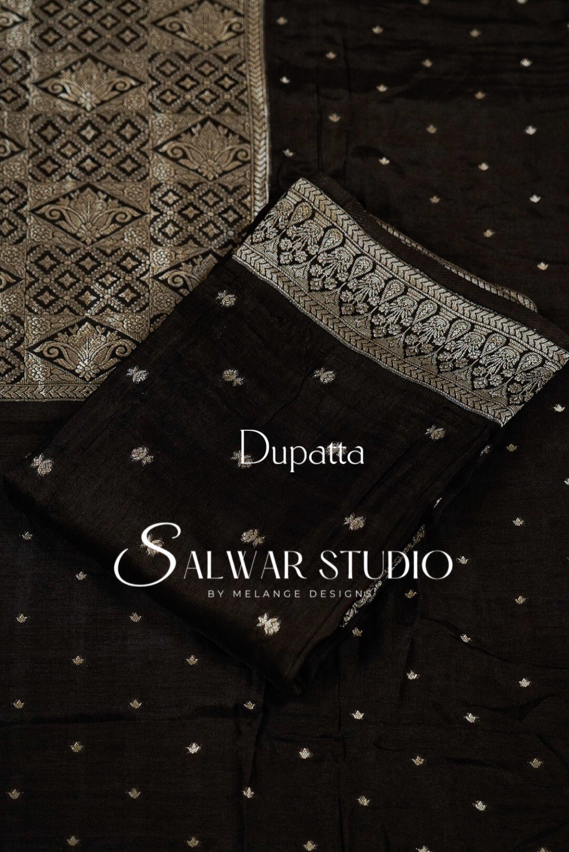 A folded black dupatta with delicate silver and white floral embroidery and a silver border with small silver motifs. 
