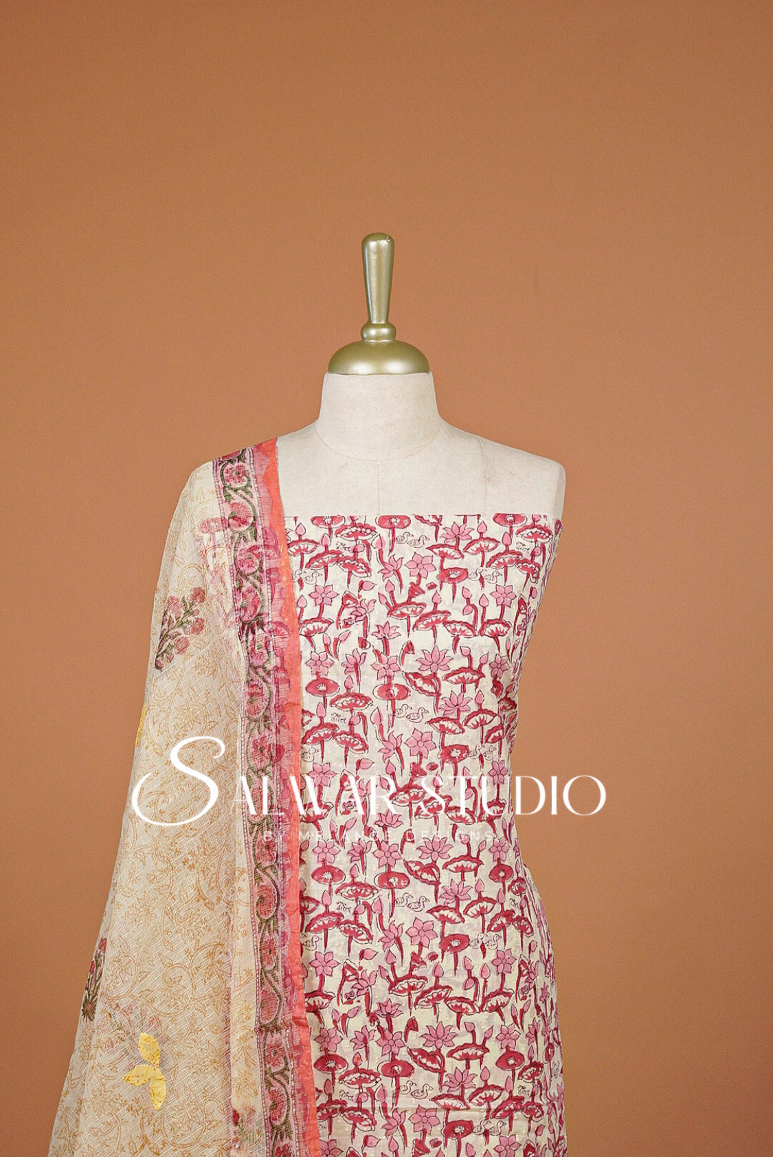 A 3-piece salwar suit set . The set features a beige printed kurta with pink flamingos, a matching pink border dupatta, and a solid pink inner border.