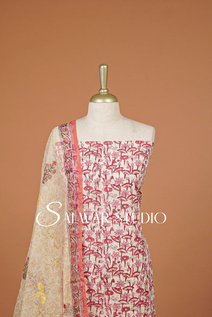 A 3-piece salwar suit set . The set features a beige printed kurta with pink flamingos, a matching pink border dupatta, and a solid pink inner border.