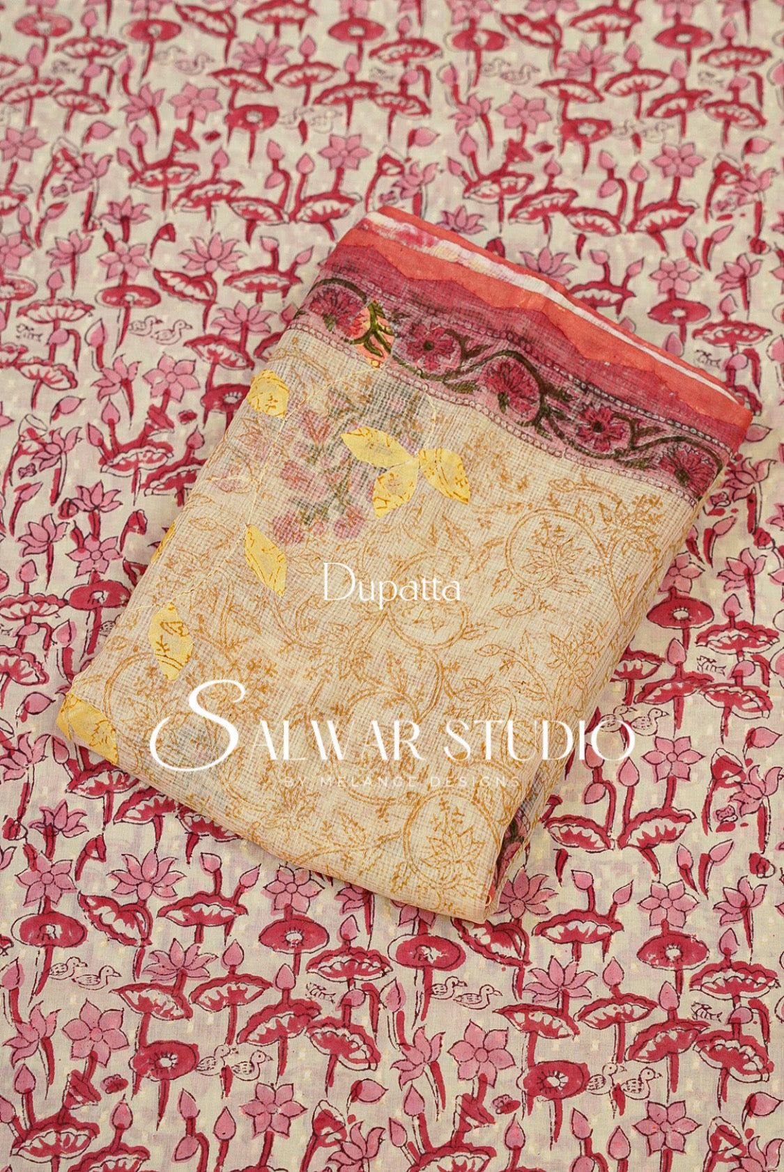 A folded beige printed fabric piece with pink and red floral motifs and a patterned border.