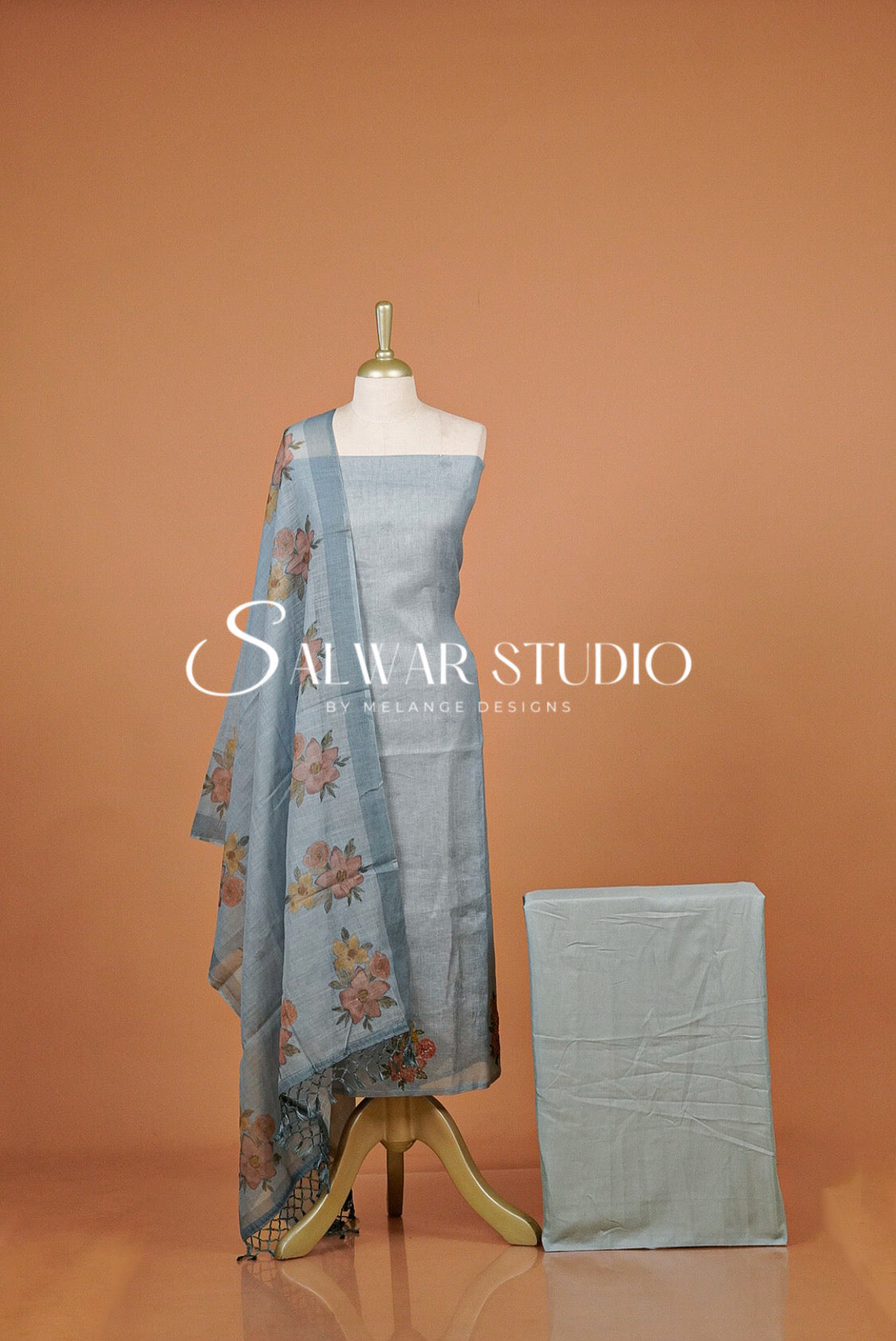 A light blue salwar suit set  featuring a floral pattern on the dupatta. The set is shown against a solid terracotta .