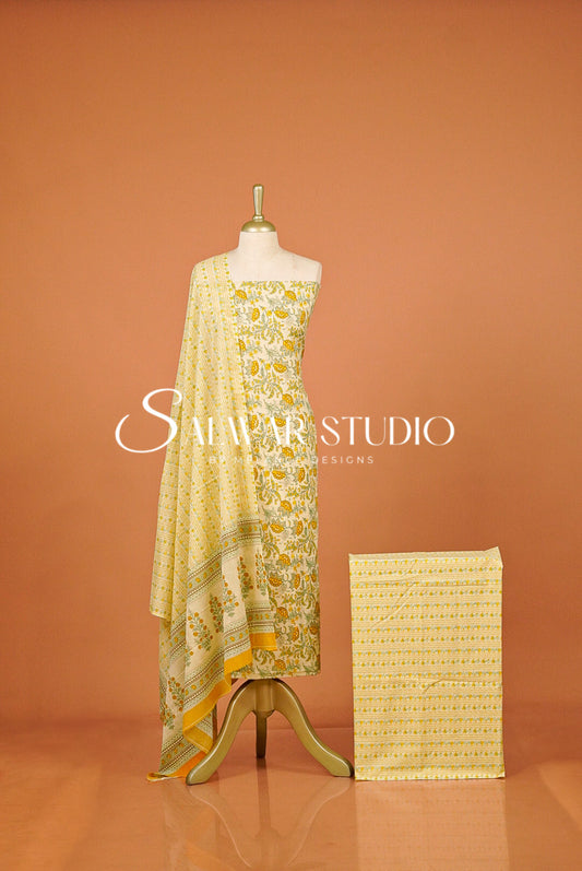 A yellow and white printed salwar suit set displayed on a mannequin, featuring a kurta, dupatta, and a folded fabric piece.