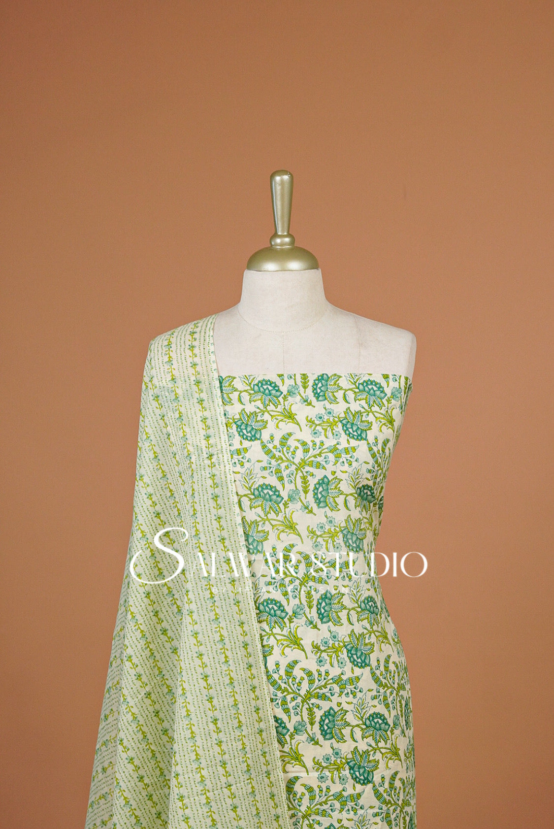 A sleeveless cream-colored dress with green floral prints and a matching patterned dupatta .