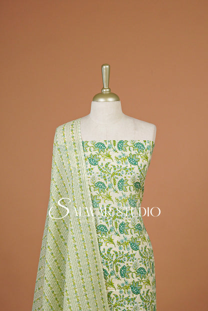 A sleeveless cream-colored dress with green floral prints and a matching patterned dupatta .