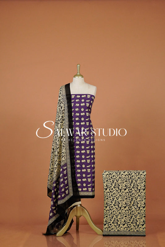 A purple and beige printed traditional outfit displayed on a mannequin, with a matching patterned dupatta draped over the shoulder . 
