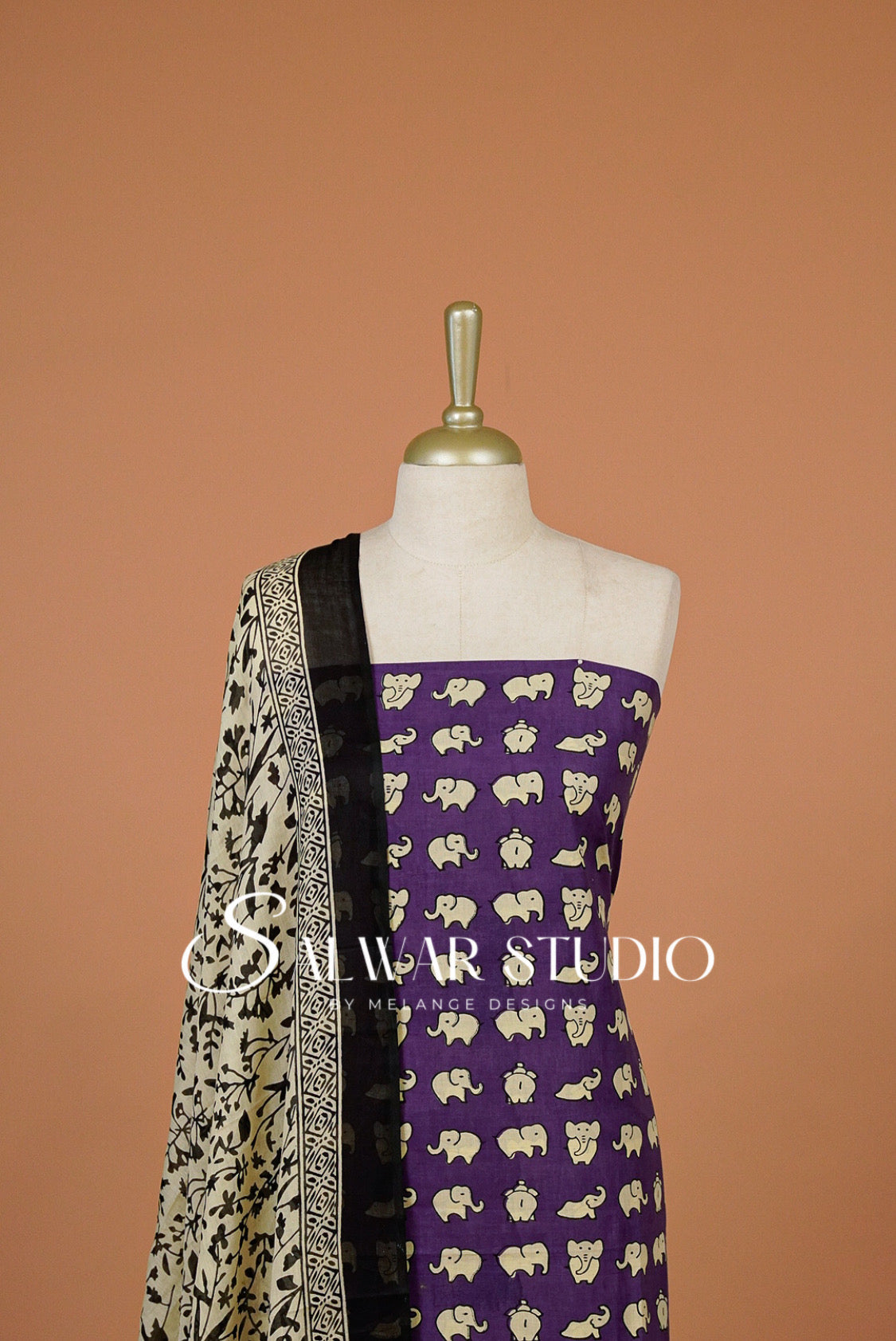 A purple salwar suit fabric with a cream elephant print and a black dupatta with cream borders.