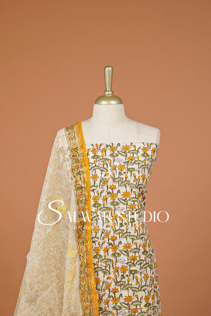 A sleeveless white or off-white salwar suit top with yellow and green floral embroidery, paired with a sheer cream dupatta featuring a yellow border.