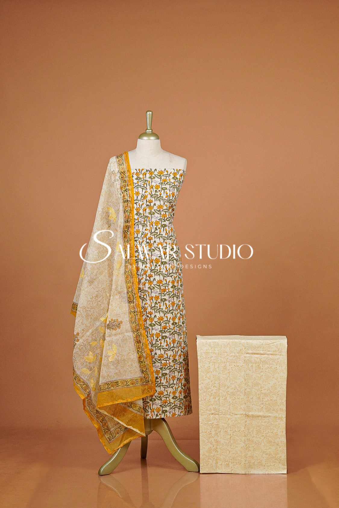 A traditional salwar suit set displayed  featuring a printed salwar, a matching kurta, and a sheer printed dupatta.
