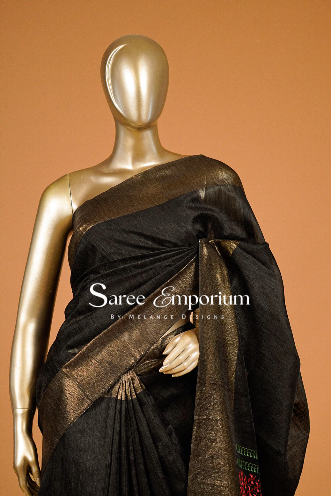 A black silk saree with a wide metallic gold border .