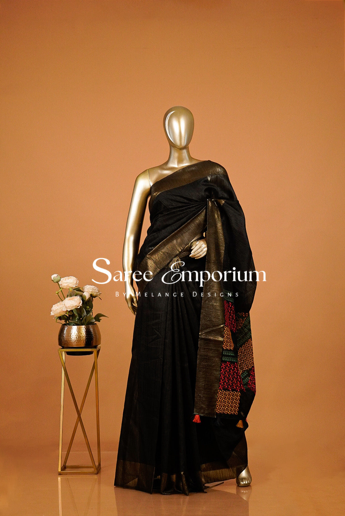 A black saree with a gold border and a multicolor patterned pallu .