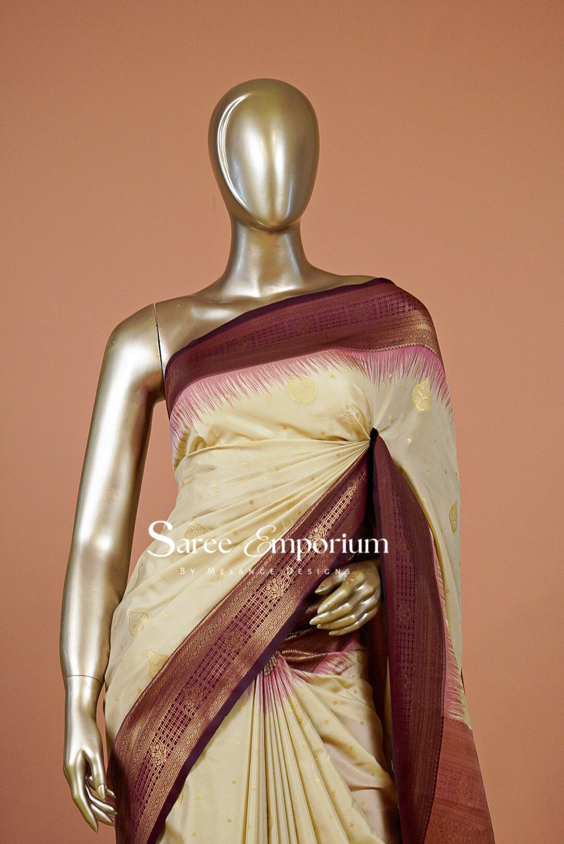 A cream-colored silk saree with a deep maroon border and gold motifs.