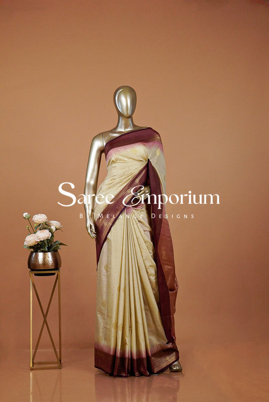 A cream and maroon silk saree draped .