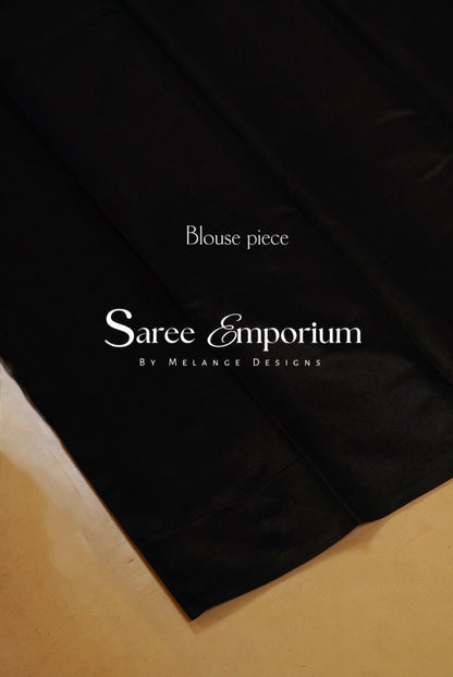 A close-up of a black fabric garment laid flat on a beige surface.