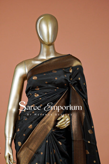 A black silk saree with gold zari motifs and a wide gold border.