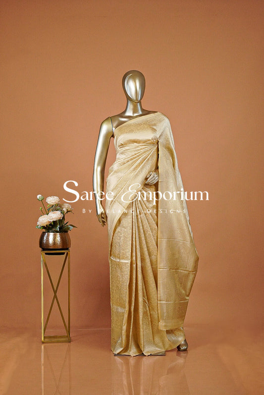 A timeless Semi Silk Saree in a rich champagne-gold shade, featuring an elegant all-over jacquard weave with intricate traditional motifs. The subtle sheen enhances its luxurious appeal, while the finely woven border and detailed pallu add depth and sophistication to the overall look.