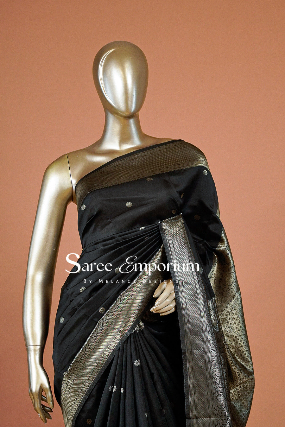 A black silk saree with a wide metallic gold border and small gold motifs.