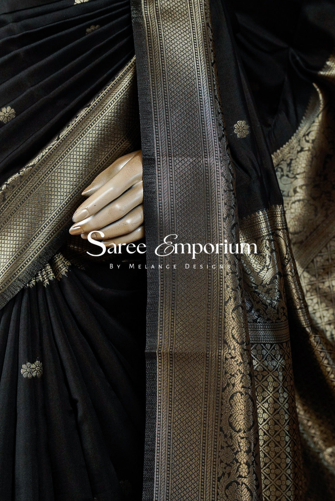 A close-up of a black silk saree with intricate gold zari brocade work .