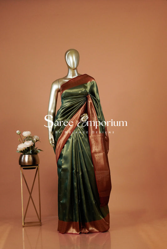 A metallic green silk saree with a rich copper-brown border is elegantly .