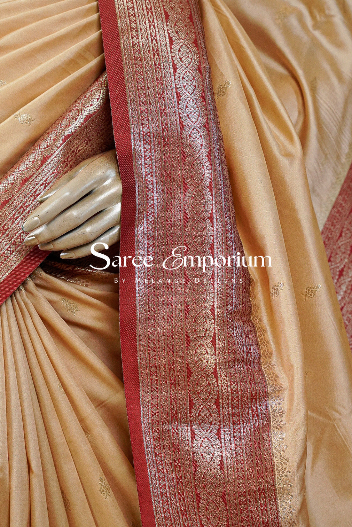 A close-up of a beige silk saree with a prominent red and gold zari border.