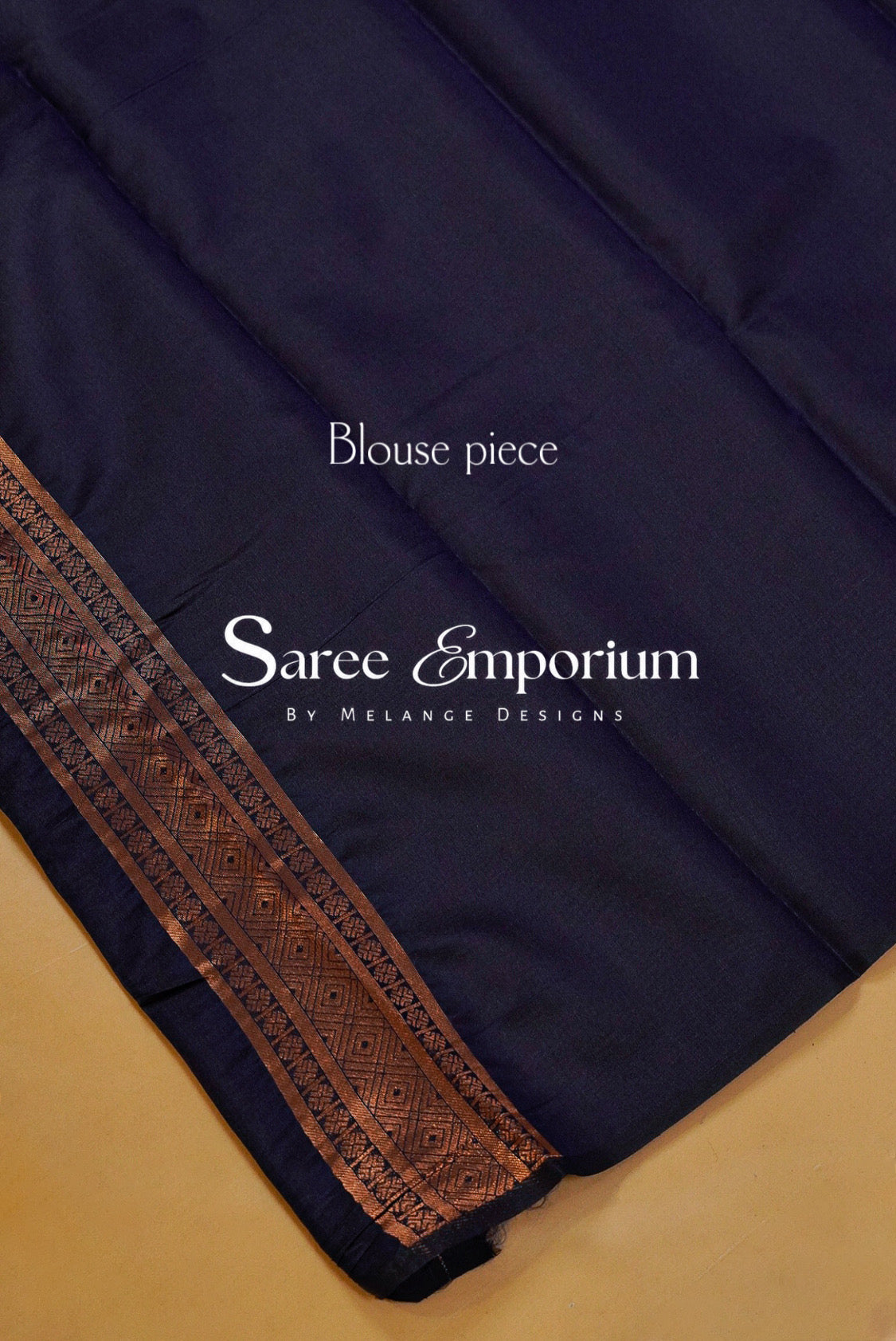 A close-up of a navy blue blouse piece fabric with a decorative copper-brown patterned border.
