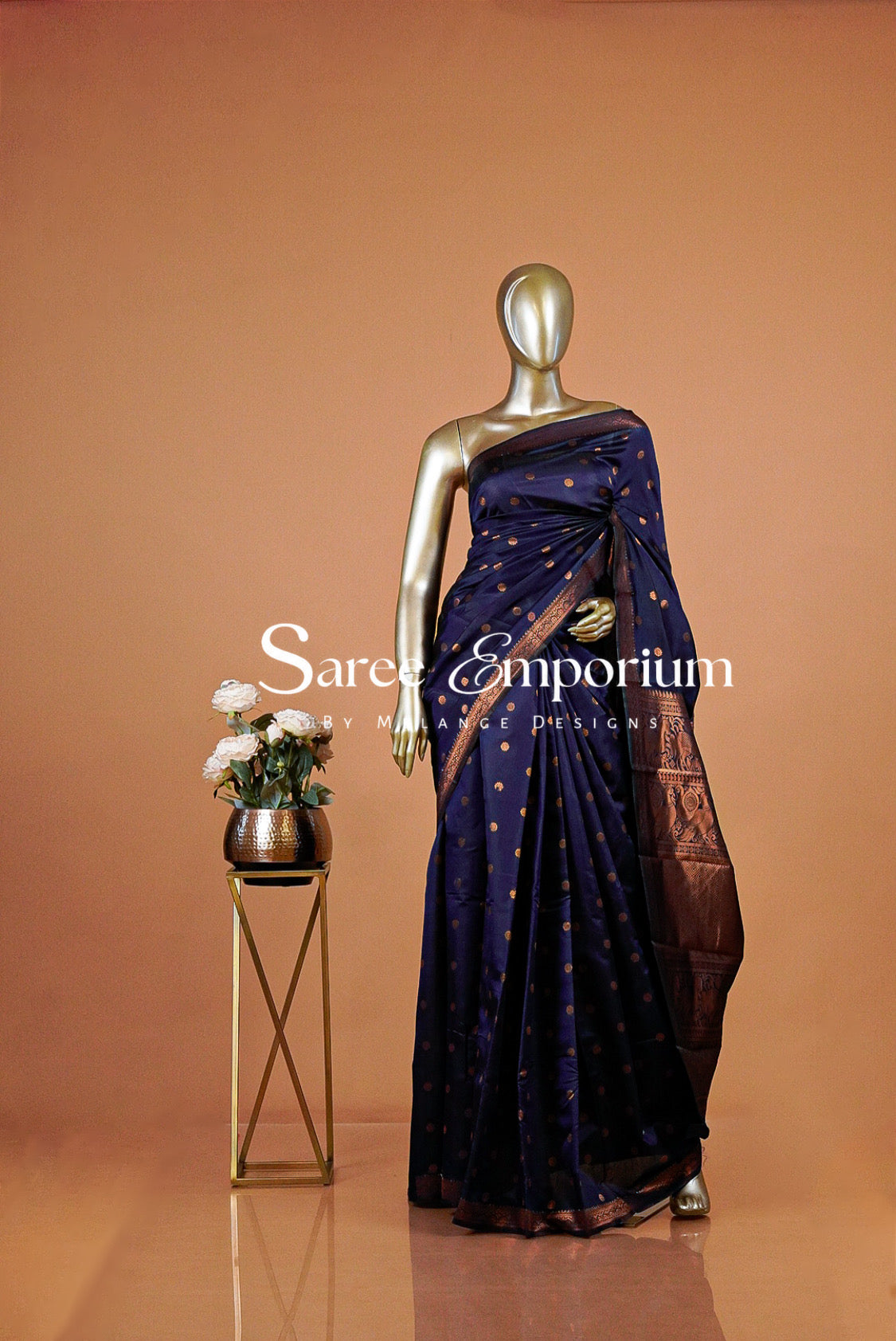 A dark navy blue saree with gold motifs and a brown border .