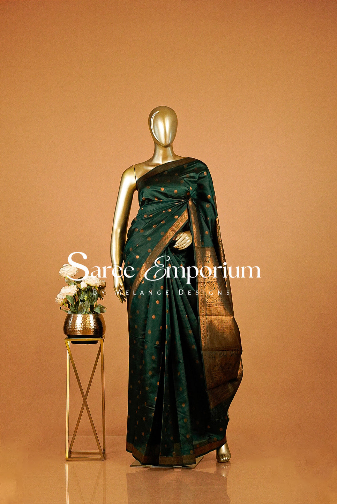 A dark green silk saree with gold motifs and a gold border.