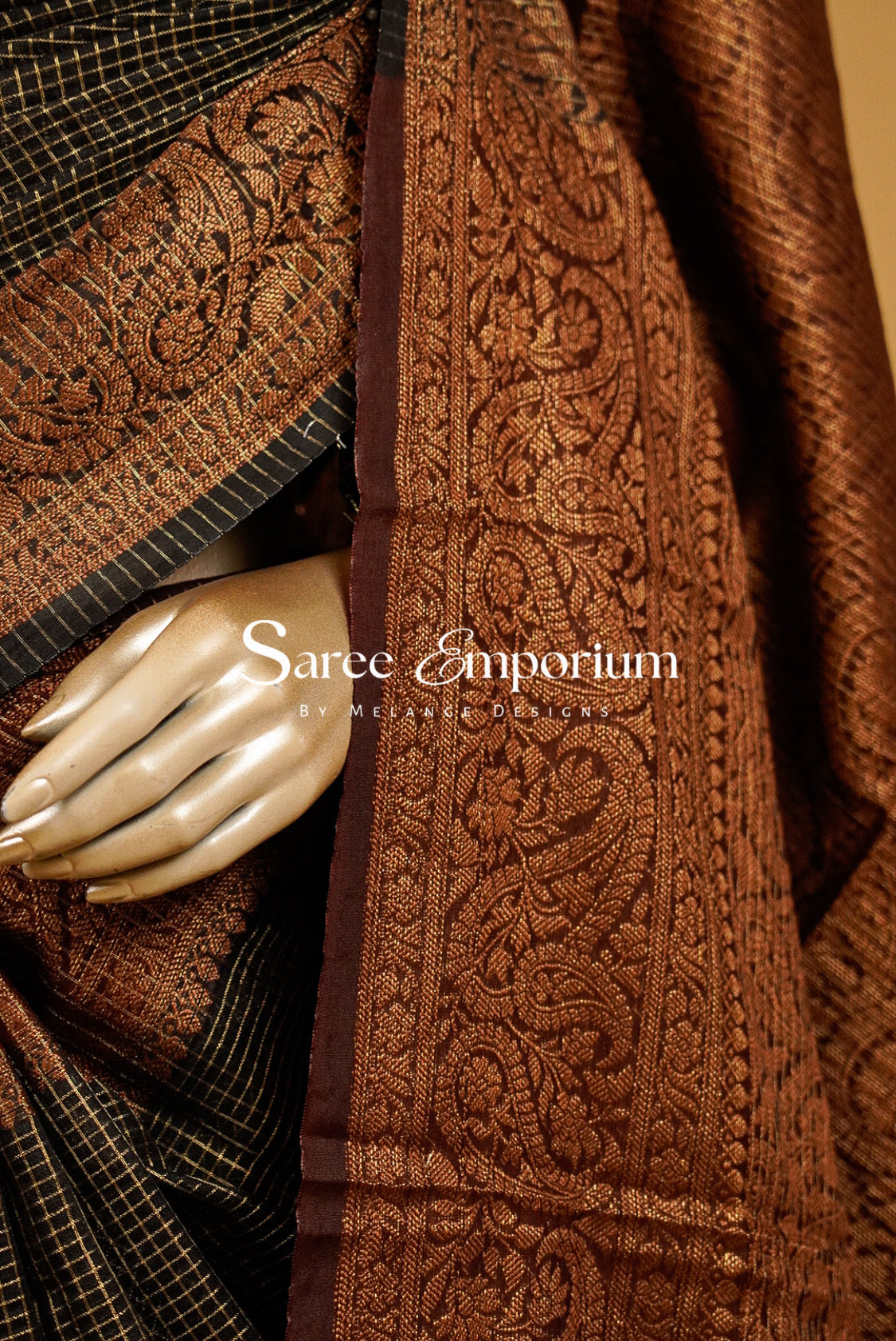 rust and gold semi silk saree. The fabric features intricate floral motifs and a checkered border.
