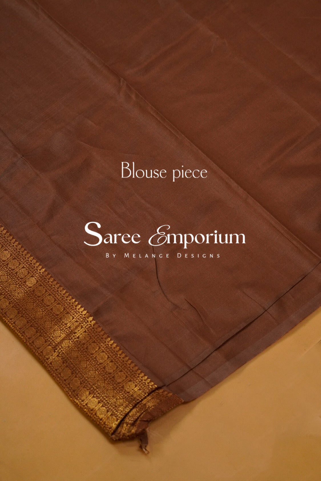 A coffe brown silk saree blouse piece with a gold zari border.