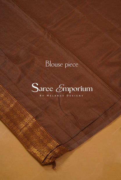 A coffe brown silk saree blouse piece with a gold zari border.