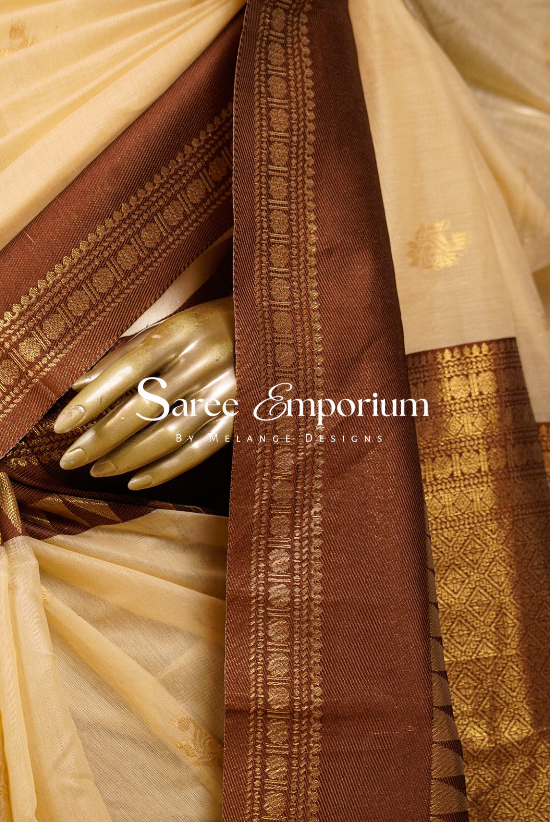 A close-up of a traditional Indian saree with a warm beige body, a rich coffe brown border, and intricate gold zari metallic embroidery.