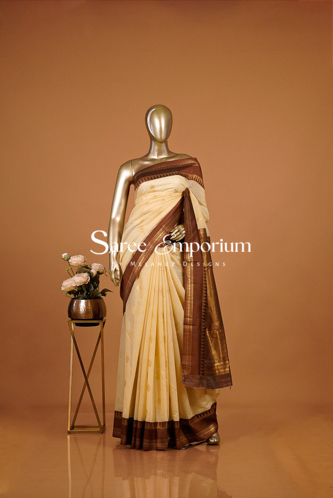 A cream and coffe brown saree  The saree has a cream body with a brown border and pallu.