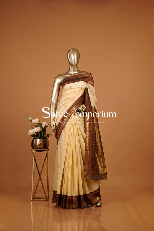 A cream and coffe brown saree  The saree has a cream body with a brown border and pallu.