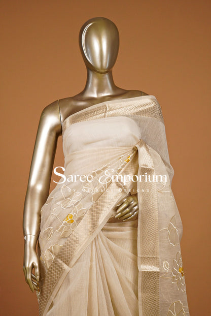 A cream-colored silk saree with gold floral embroidery.