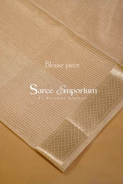 A close-up of a beige saree fabric with fine vertical stripes and a woven border.