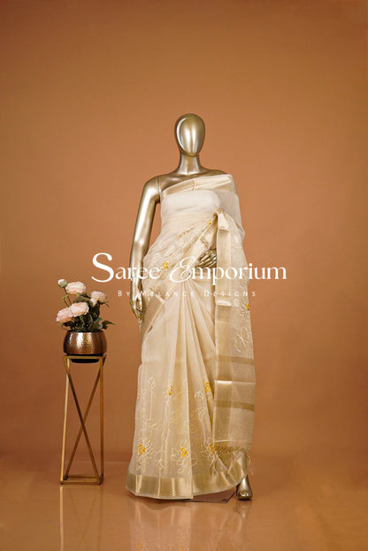 A cream-colored silk saree with gold zari embroidery .