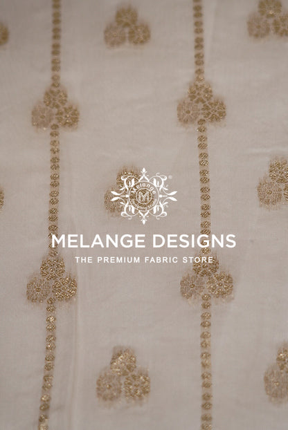 Close-up of a light beige Viscose Jaqured Dyeable Fabric with vertical gold embroidered patterns.