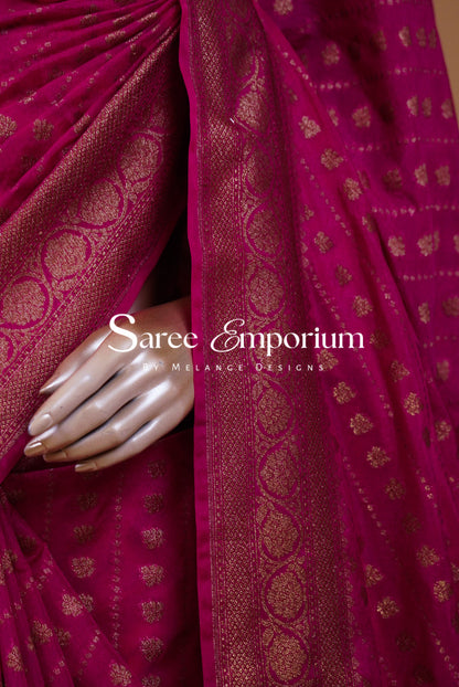 A close-up of a magenta pink saree with gold zari woven patterns.
