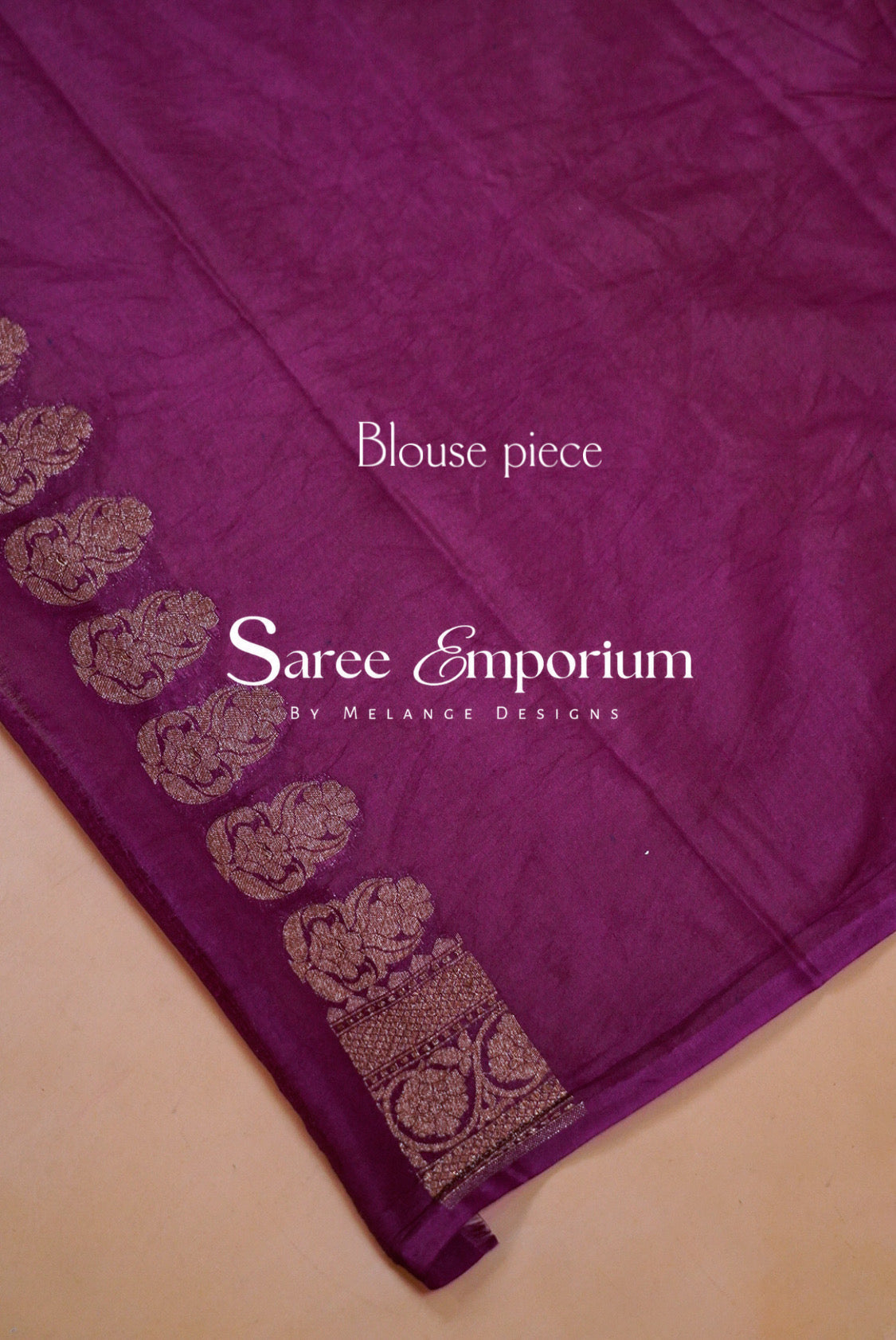 A close-up of a purple sari fabric piece with a decorative border featuring metallic gold motifs .