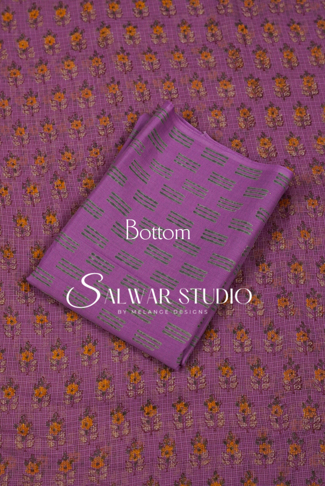 A folded piece of purple fabric with a repeating orange and yellow floral pattern and gray text blocks.