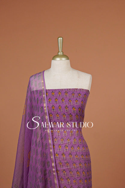 A lavender purple salwar suit set .The set includes a solid purple fabric top with small gold and yellow floral embroidery .