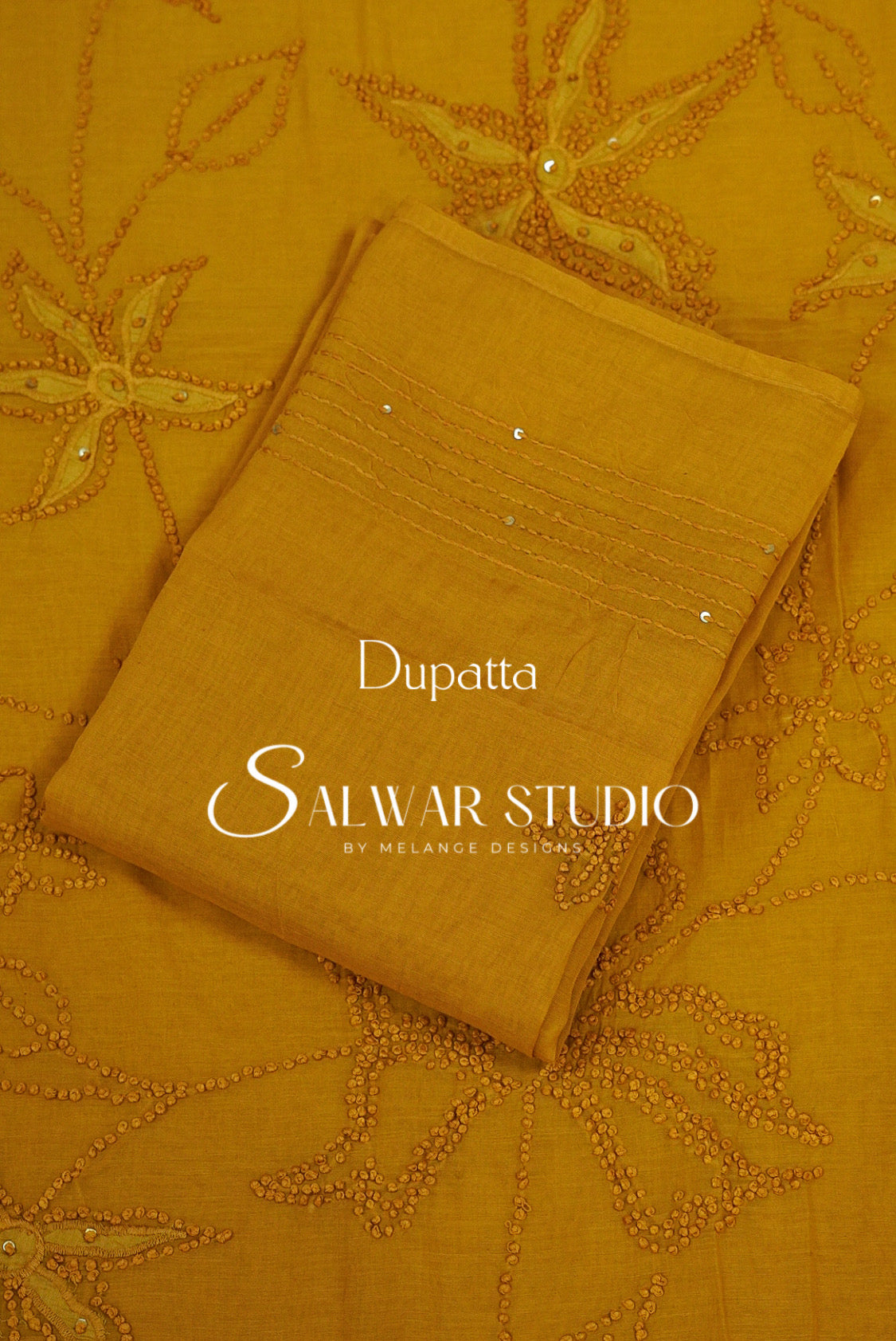 A folded mustard yellow dupatta with floral embroidery and beadwork.