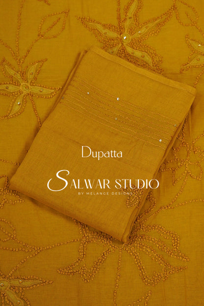 A folded mustard yellow dupatta with floral embroidery and beadwork.