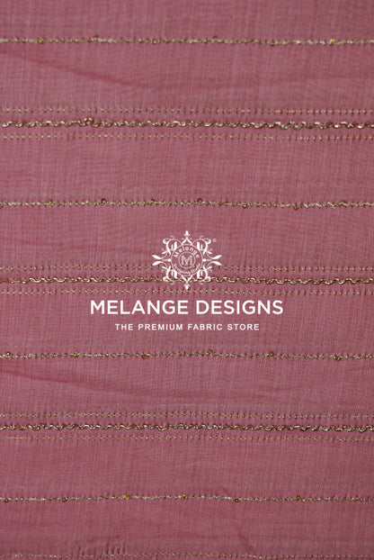 A close-up of dusty rose pink Chanderi Silk Embroidery Fabric with horizontal metallic gold stripes .