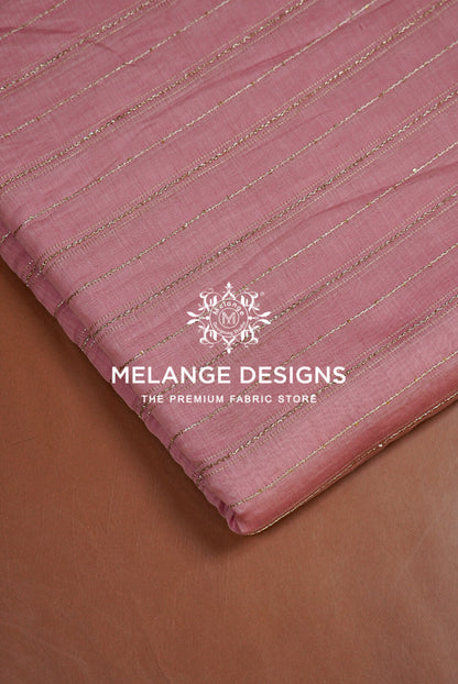 A close-up of a dusty pink Chanderi Silk Embroidery Fabric with thin metallic gold stripes, folded over to show its texture and sheen.