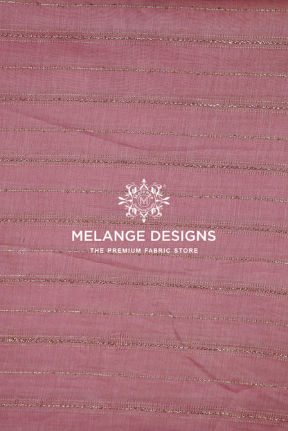 A close-up of dusty rose pink Chanderi Silk Embroidery Fabric with horizontal metallic gold stripes .