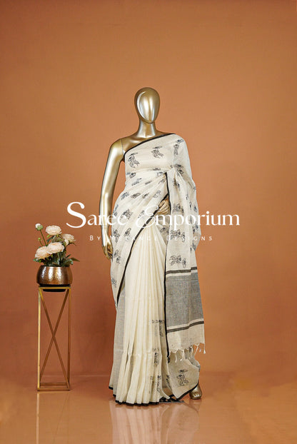 A cream and gray saree with black floral motifs .The saree features a pleated body and a draped pallu with a gray border.