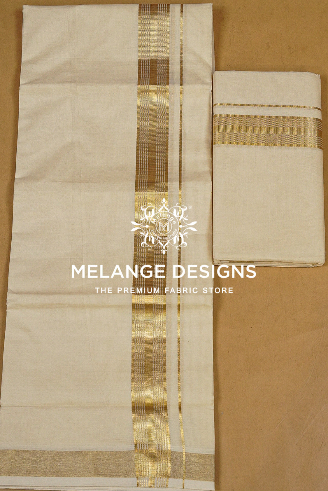 An off-white cotton dhotis featuring a prominent gold zari stripe down the center and a matching gold border along the bottom. A folded matching fabric piece is shown on the right.