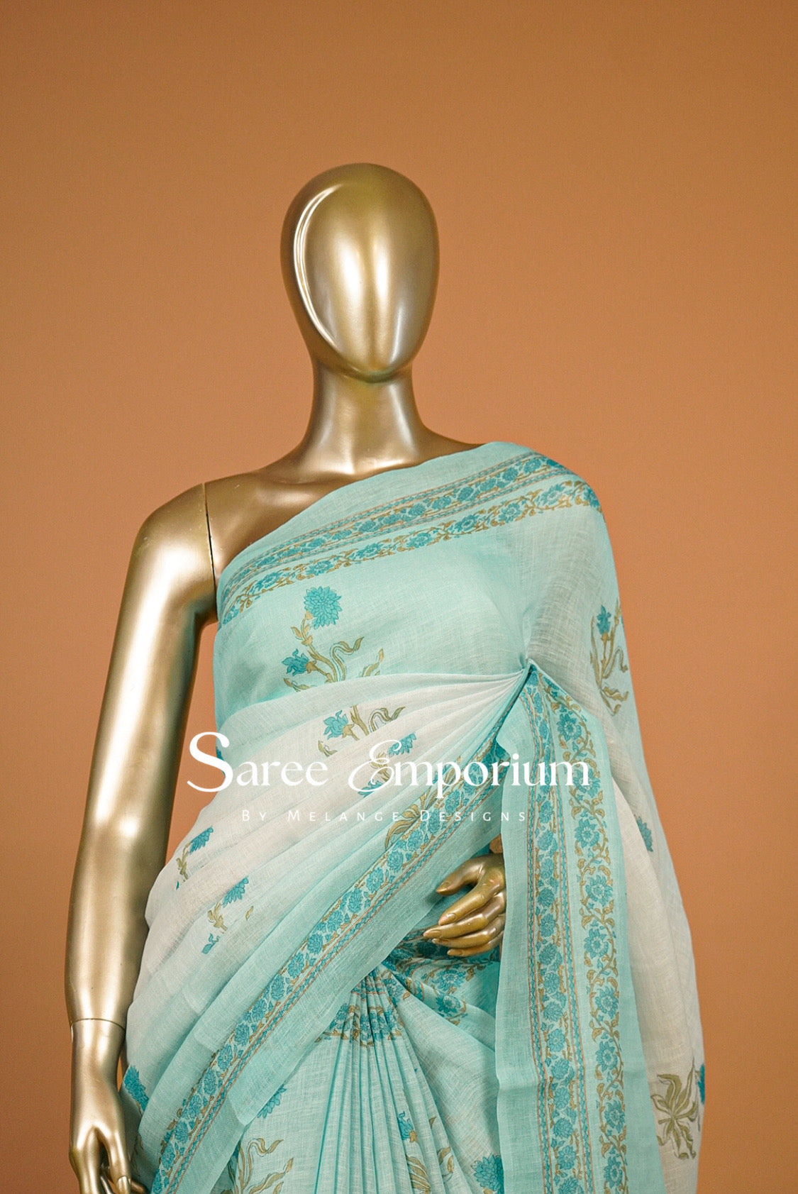 A light aqua blue and white saree with gold border and floral prints .
