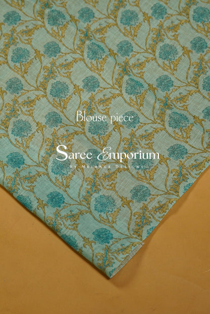 A folded piece of light blue-green sari fabric with a gold floral vine pattern.