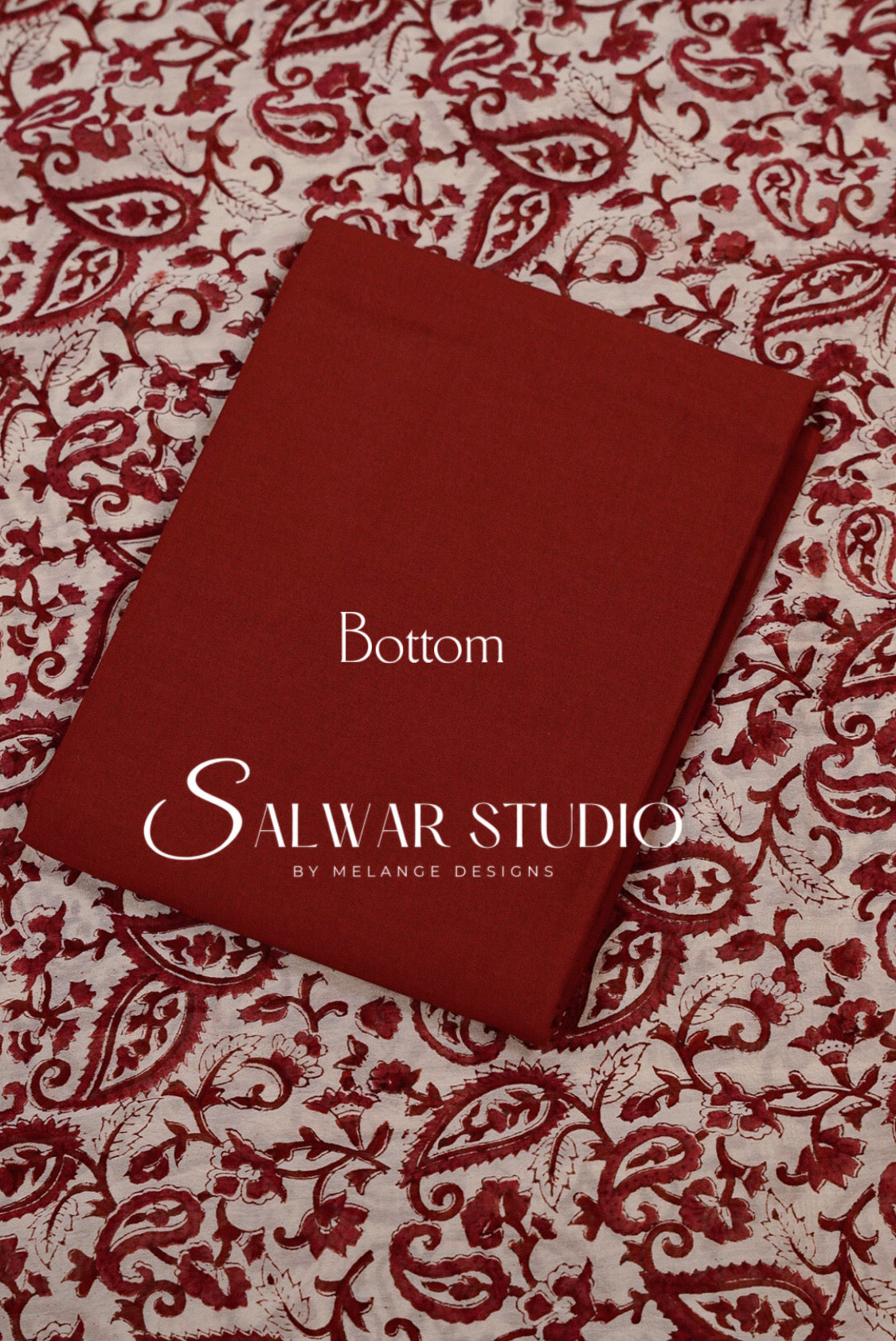 A red fabric bottom panel with 'printed on it, laid flat on a red and beige paisley patterned fabric background.